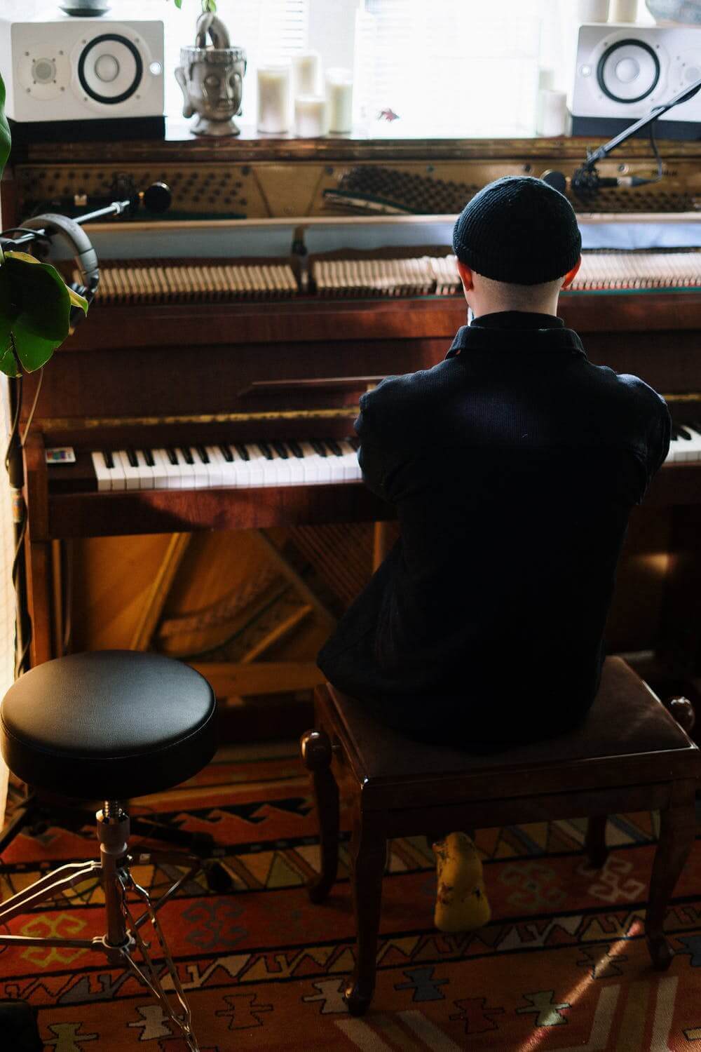 Man wearing a hat sat at piano, playing it