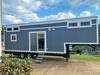 Gooseneck tiny house from Greensburg, PA; outside shot showing the five windows, double doors (with windows) and blue wood cladding. Gooseneck tiny house from Greensburg, PA; outside shot showing the five windows, double doors (with windows) and blue wood cladding.