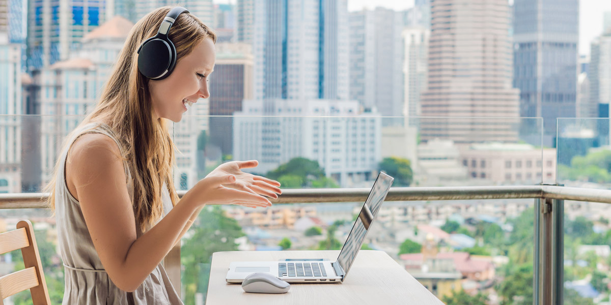Can data analysts work remotely? A remote data analyst in side profile, smiling at a laptop screen against a city backdrop