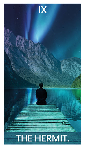 The Hermit card. A man sits on the edge of a lake, under an aurora.