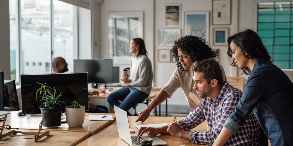 UX Trends in 2021 A group of designers gathered around a desk in an office, discussing a project