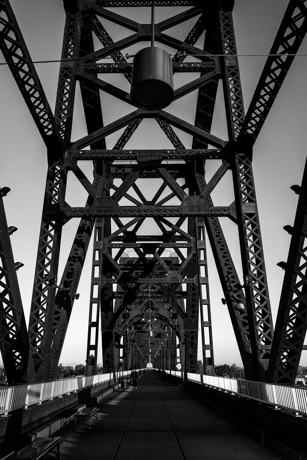 Looking north towards Indiana along a steel footbridge crossing the Ohio River. A large number of pedestrians are walking along the footbridge towards the photographer.