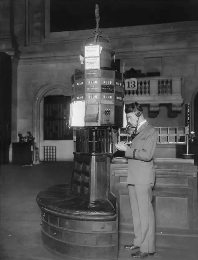 a man stands next to an old financial machine, black and white