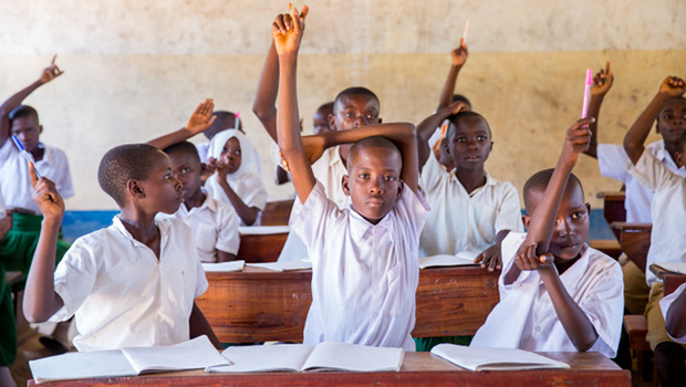 Children in a classroom raise their hands