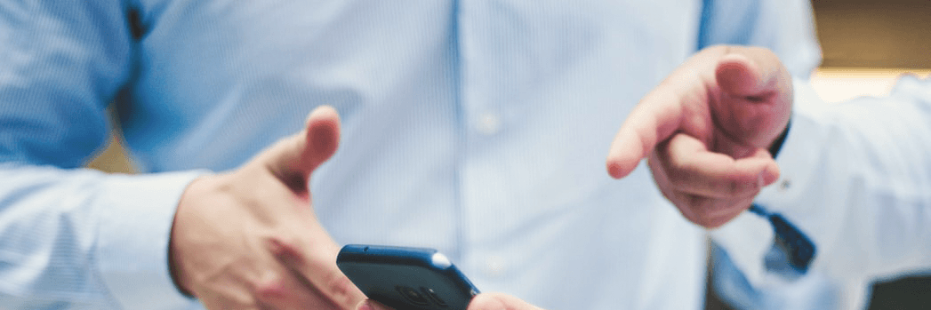Männer in blauen Hemden zeigen auf App-Programmierung auf ihrem Smartphone