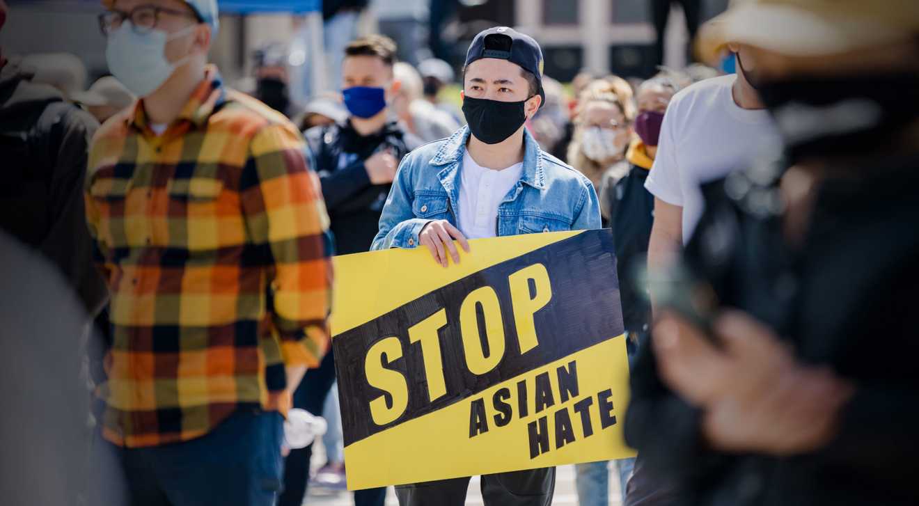 A man holds a #StopAsianHate sign at a large rally