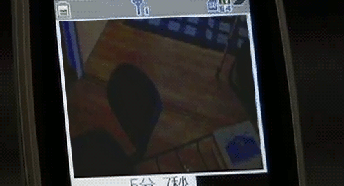 An animated gif of a scene from the movie 'Marebito' of surveillance footage seen from an old cell phone showing a girl running on all fours.