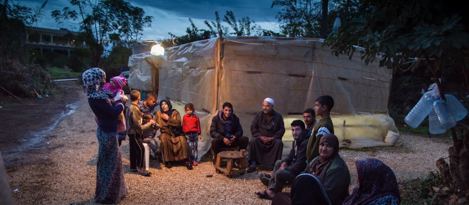 Syrian refugees gather at evening around an informal tented community in Lebanon