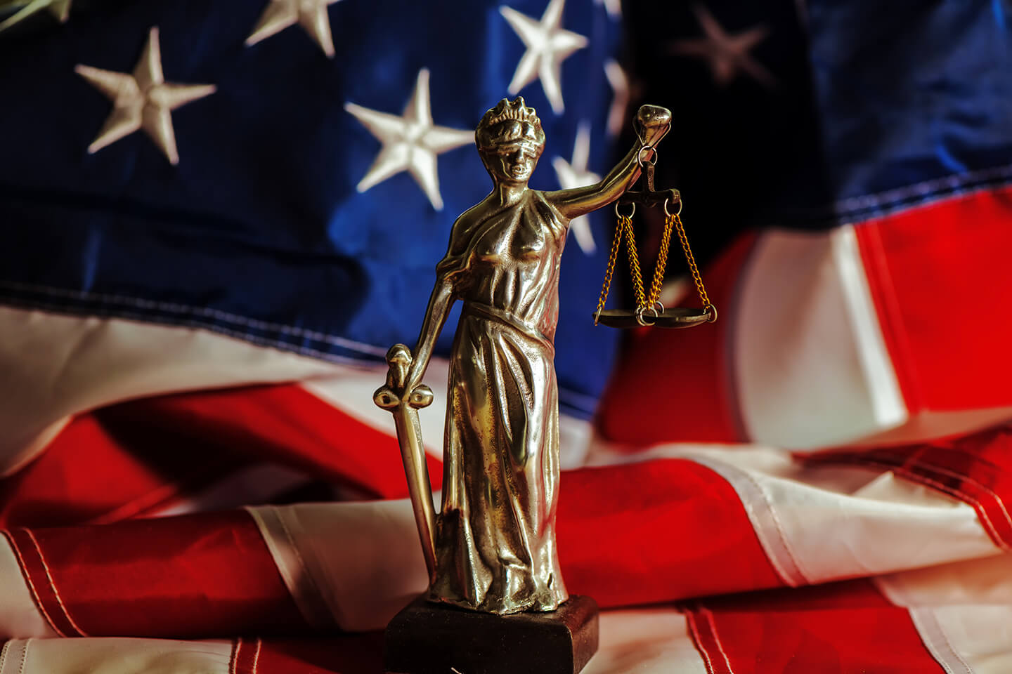 a statue of Lady Justice in front of an American flag