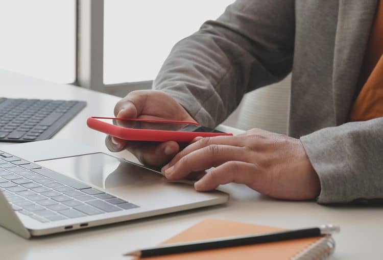 Kunde vor Laptop mit Smartphone Kunde vor Laptop mit Smartphone
