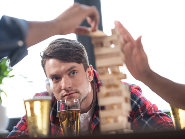 A man observing the Drunk Jenga tower as other players pull pieces