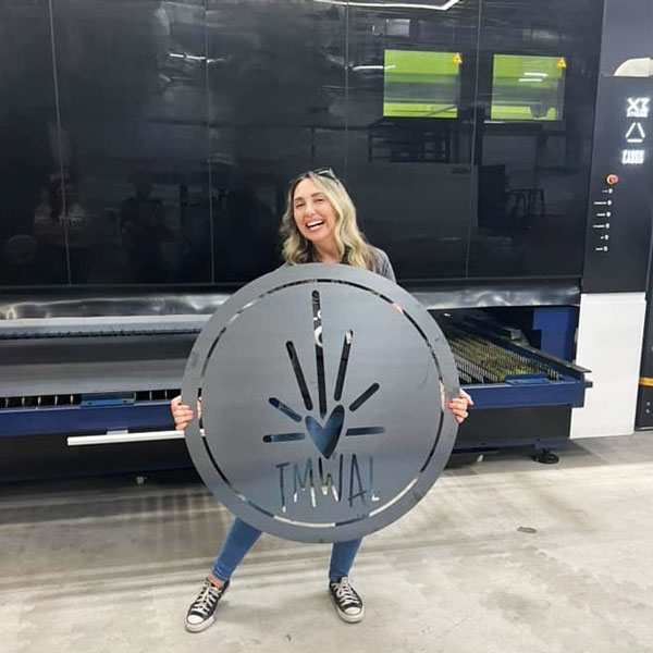 person holding a large round metal cut sign