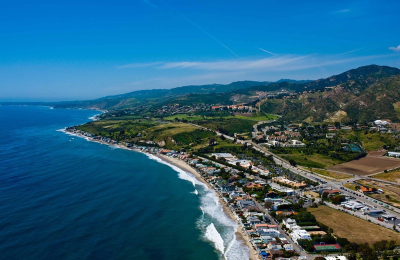 Aerial view of Pepperdine University malibu campus showing waves breaking on the coastline and a green hillside