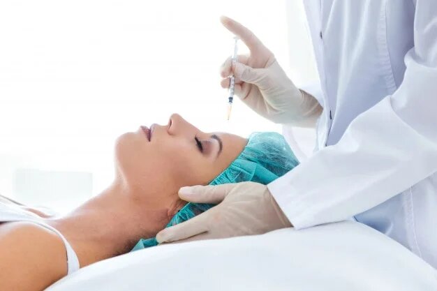 Female patient receiving needle injection to her forehead