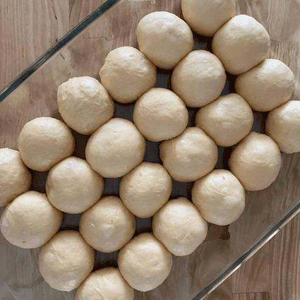 Divide the dough into 24 equal rolls (about 45 grams each), shape into balls, and place in a buttered 9x13 baking dish. Let rise a second time until the space between the rolls has disappeared, 3-6 hours.