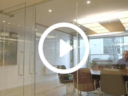 Contemporary office meeting space enclosed by interior glass walls containing brown metal framed chairs and black table Skype background