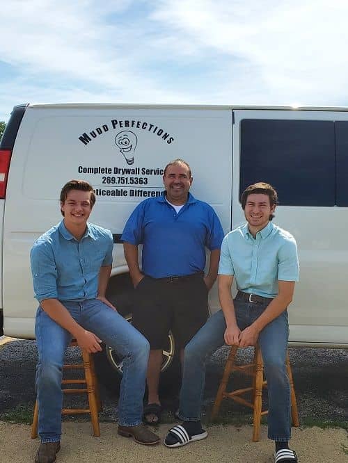 three men posing in front of the mudd perfections truck