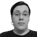 Monochromatic photo of a caucasian male in his early twenties, slightly overweight, shoulder-length hair tied at the back, wearing slightly crooked square-framed glasses and a black shirt upon an empty background