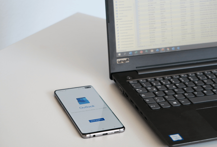 Access Outlook Smartphone mit Outlook-App und Laptop mit Access-Tabelle