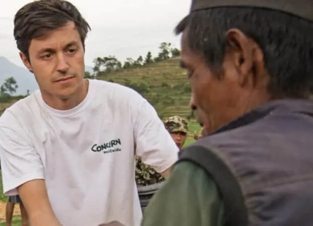 Concern Worldwide’s Kirk Prichard hands a man a tarp at a distribution in Botase, Nepal.