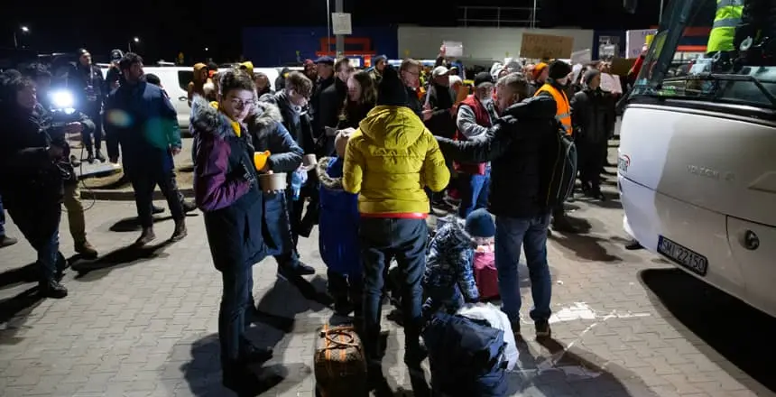 Families seeking refuge from conflict in Ukraine board buses at a reception center in Przemysl, Poland