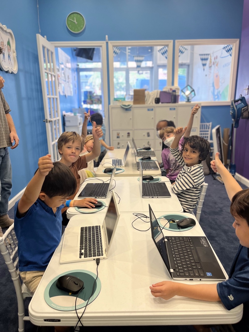 Young chess players gathered around a table learning to code
