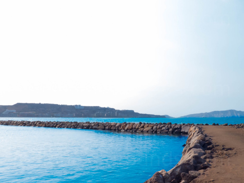 Rocky coastal path next to bright blue water Zoom background