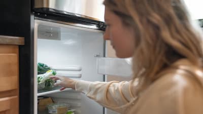 A woman getting food out of the fridge.