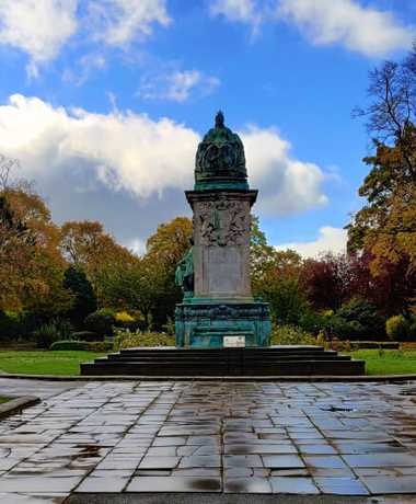 Statue at Woodhouse Moor/Hyde Park against a blue sky and wet ground