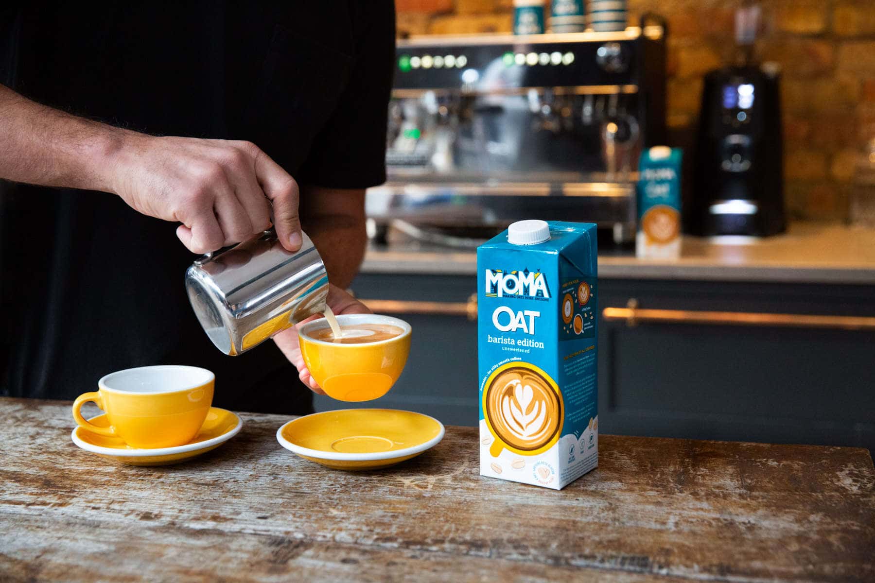 Moma barista oat milk being poured in front of a coffee machine in a cafe