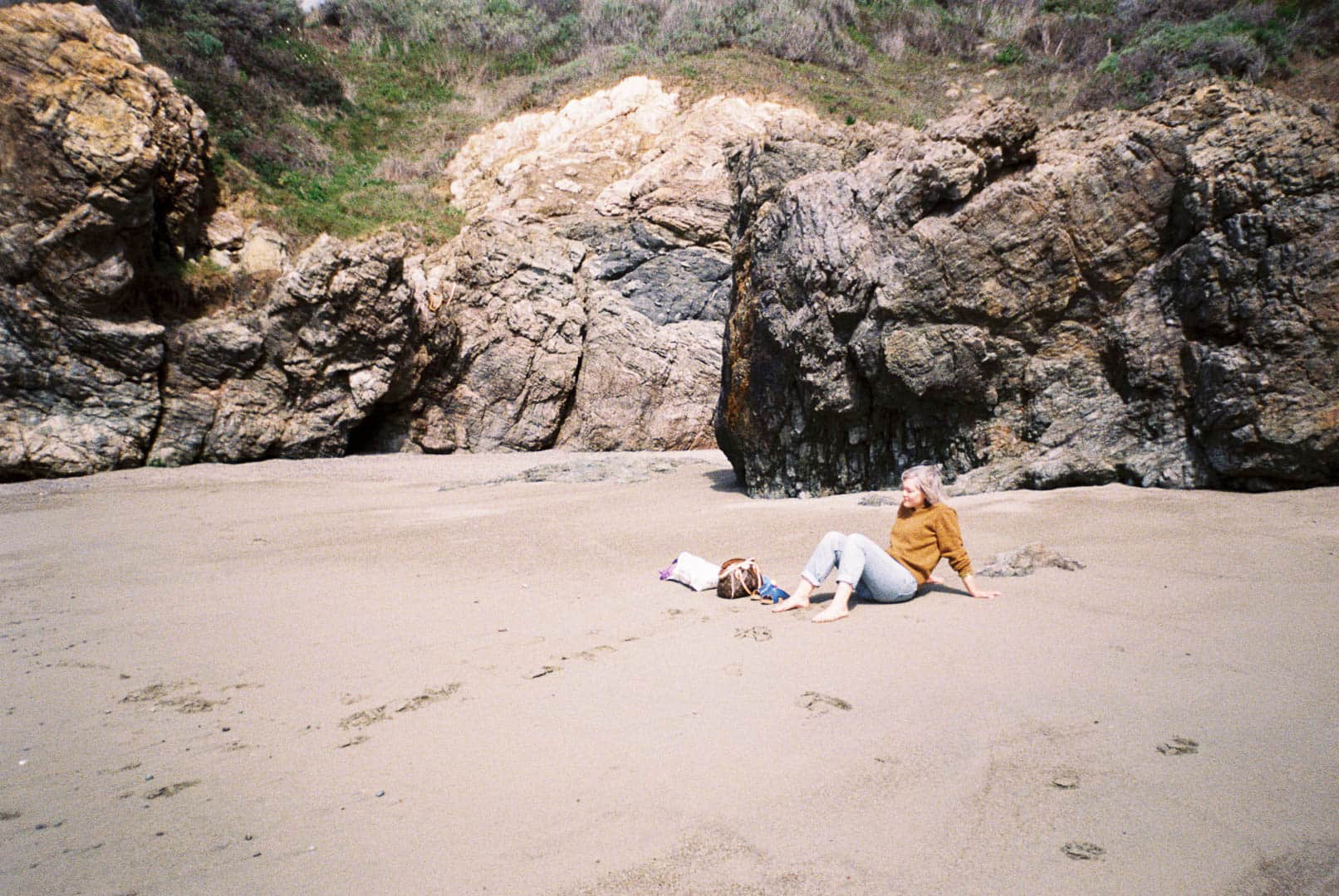 A woman sitting on a rocky beach