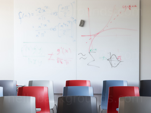 Educational style shared workspace featuring prominent whiteboard behind multi-coloured chairs Google Meet background