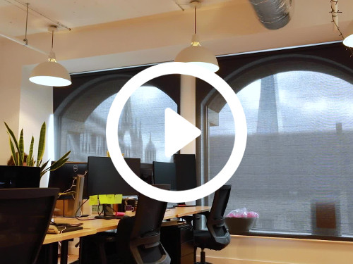 Modern shared workspace featuring wooden floor design with multiple wooden computer desks and black office chairs  Skype background