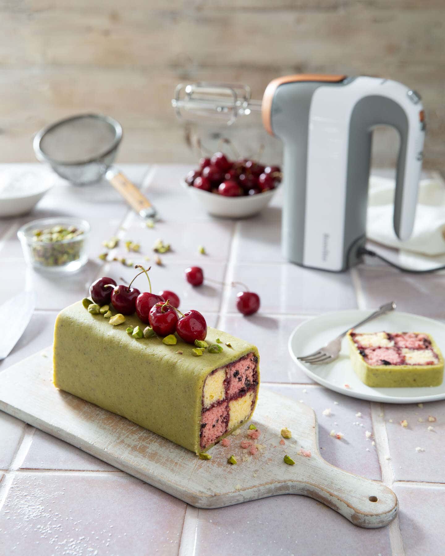 Battenberg cherry cake with pistachio marzipan with the Breville heat soft mixer with baking utensils , cherries and nuts.