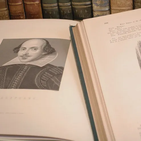 An open book showing a picture of William Shakespeare and one of his texts.