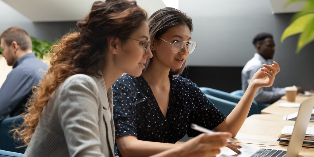 Should you do a data degree or a bootcamp? Two data analysts in side profile, sitting at a desk, looking at a computer screen