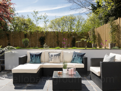 Stylish outdoor seating area with cream corner sofa and simple rear lawn Zoom background