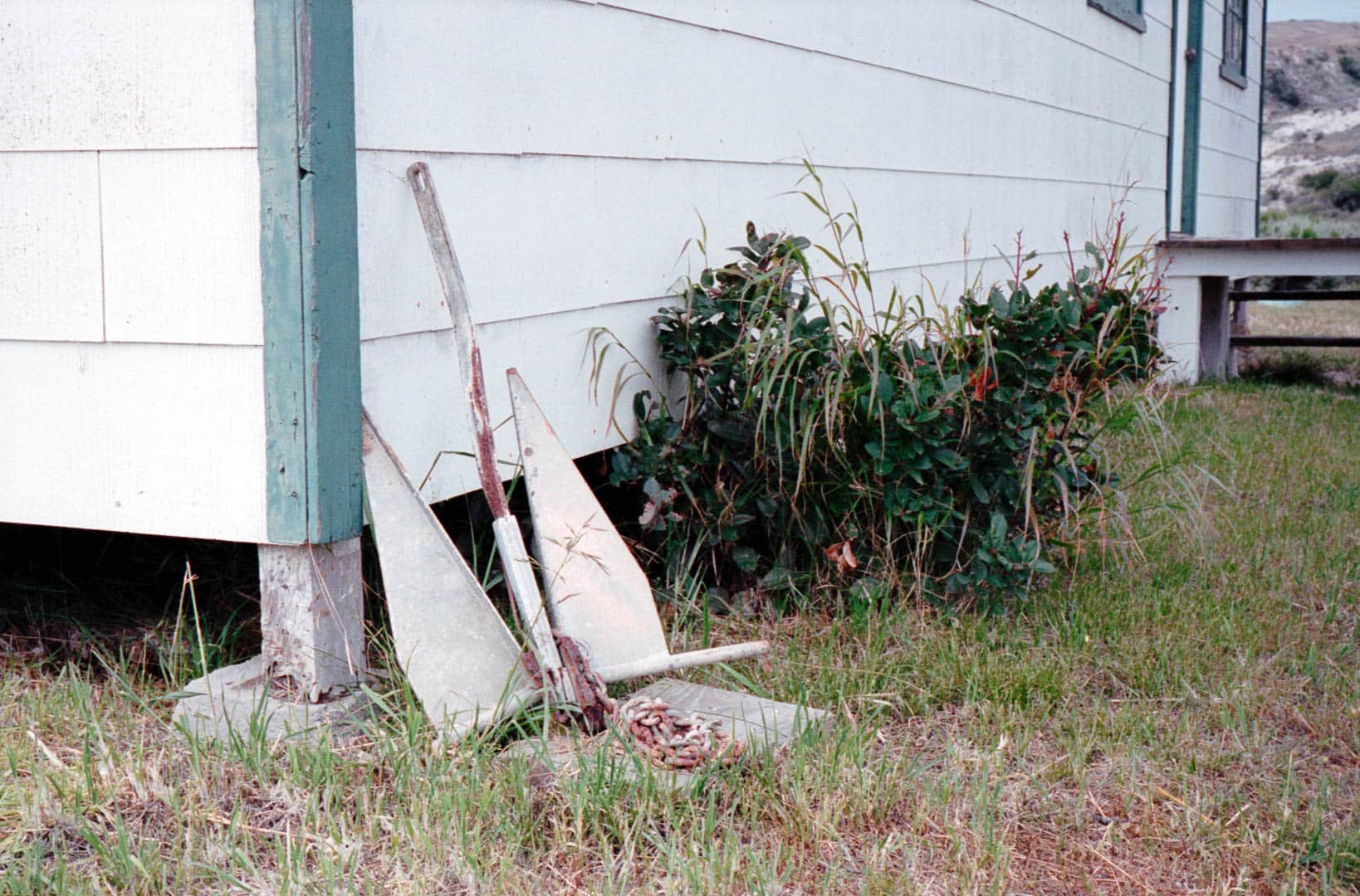 A boat anchor leaning against a wooden building