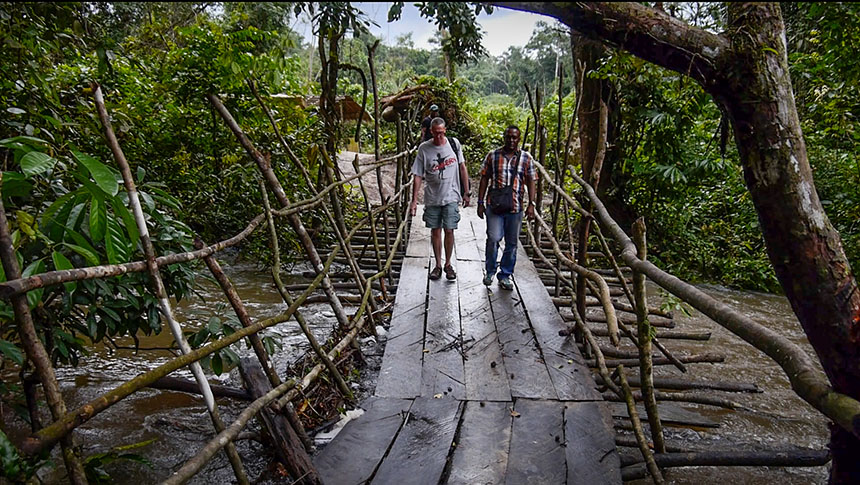 Two men crossing a rough wooden bridge in Liberia