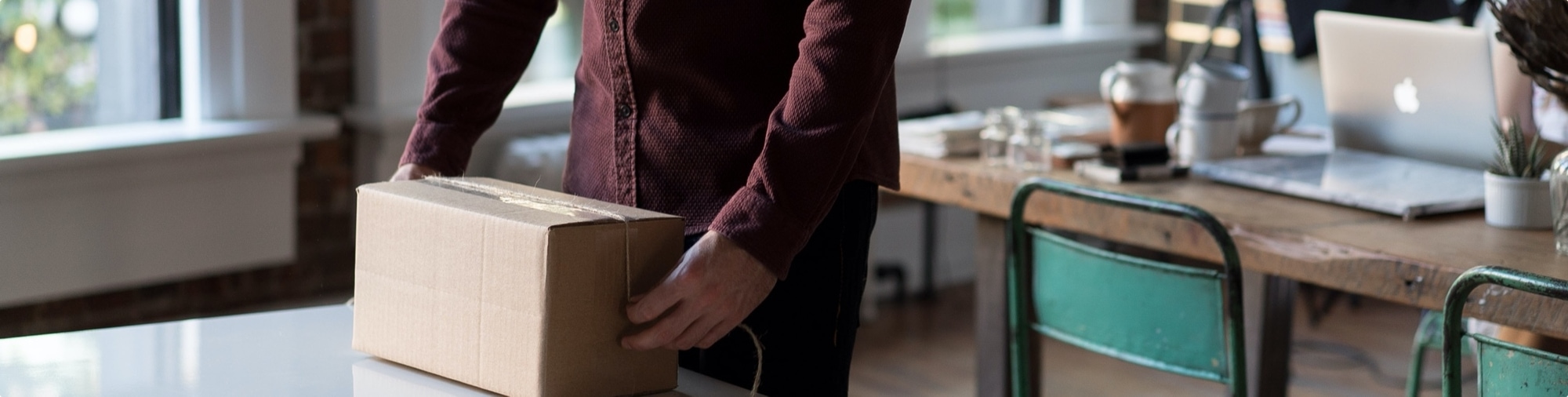 Close up image of a man wrapping a package in his home office