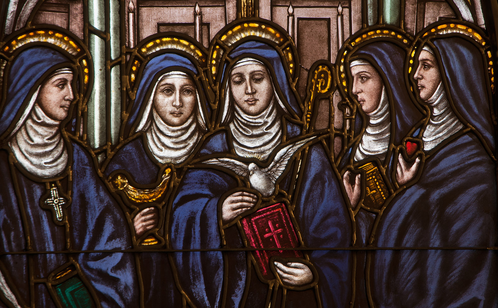 blue and red stained glass window depicting five nuns in habits