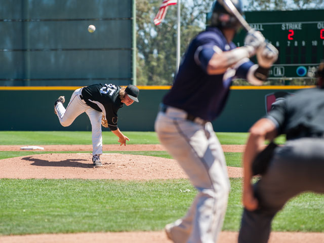 A baseball pitcher throwing the baseball toward home plate