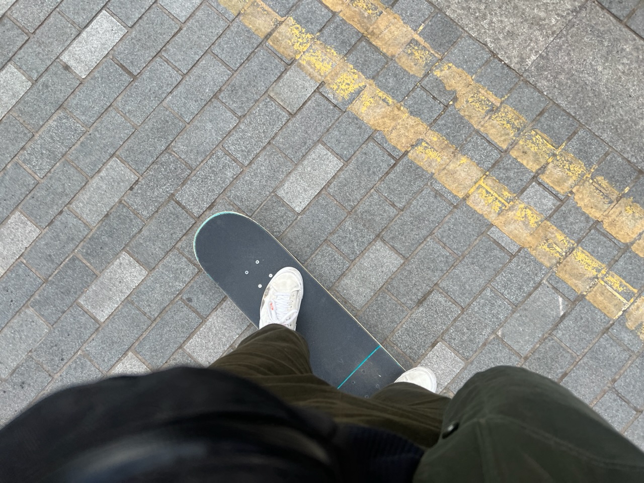 POV view of me riding skateboard on brick road 