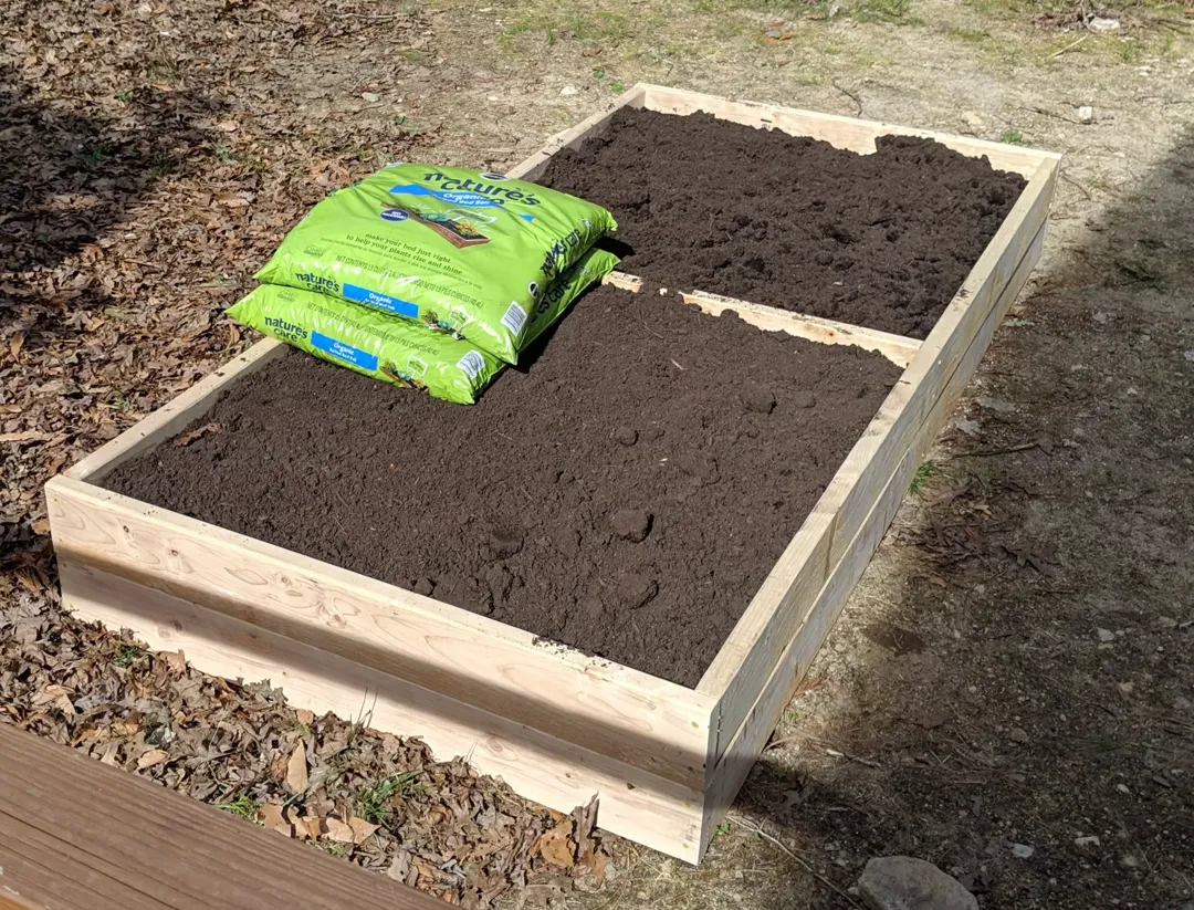 Raised garden bed filled with soil.