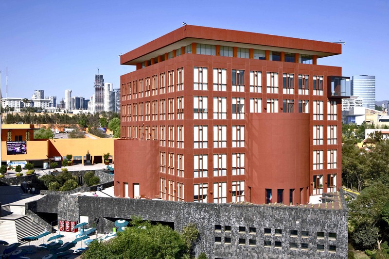 A reddish brown building on the EGADE Business School campus with other Monterrey buildings in the background