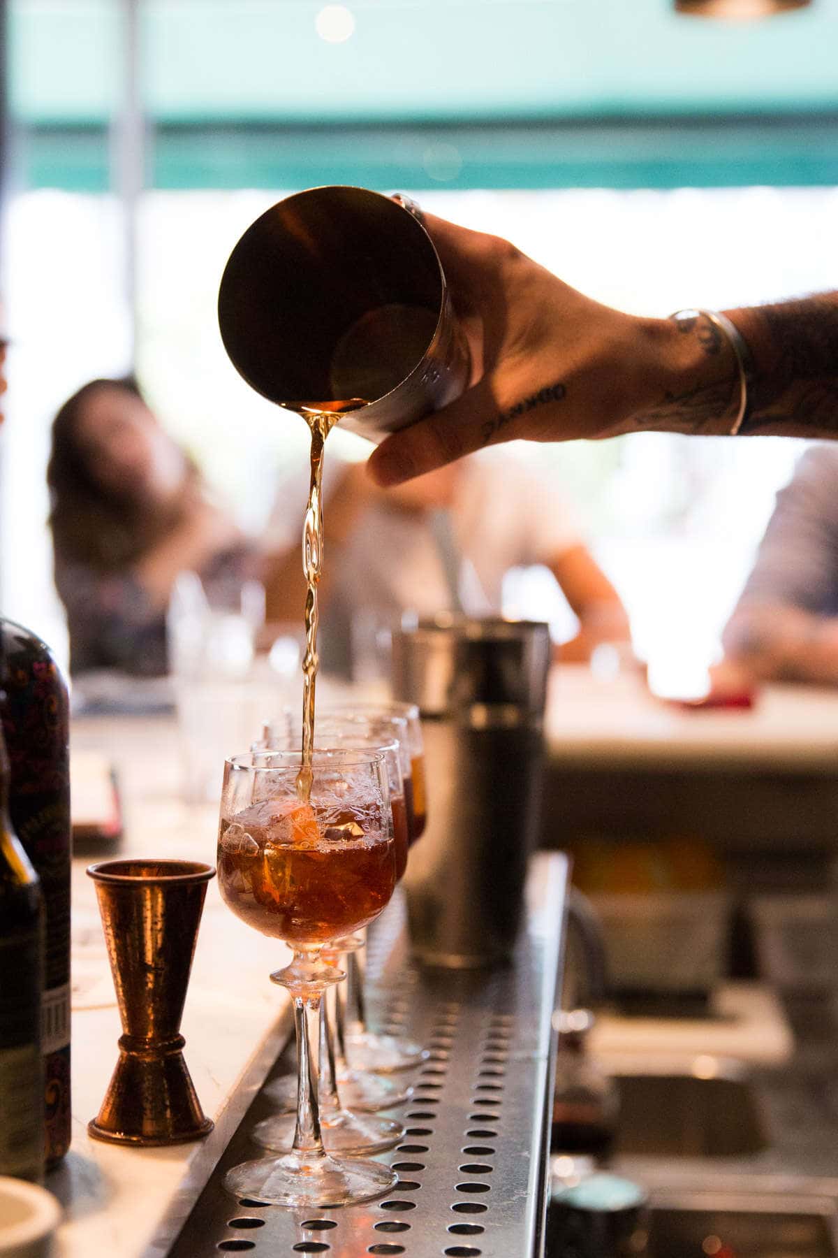 A cocktail being poured into glasses
