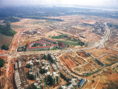 Aerial photo of construction work for the development of Sengkang New Town. An isolated Punggol Rural Centre is surrounded by a wide expanse of barren land. A few clusters of flats are being constructed beside the Centre.