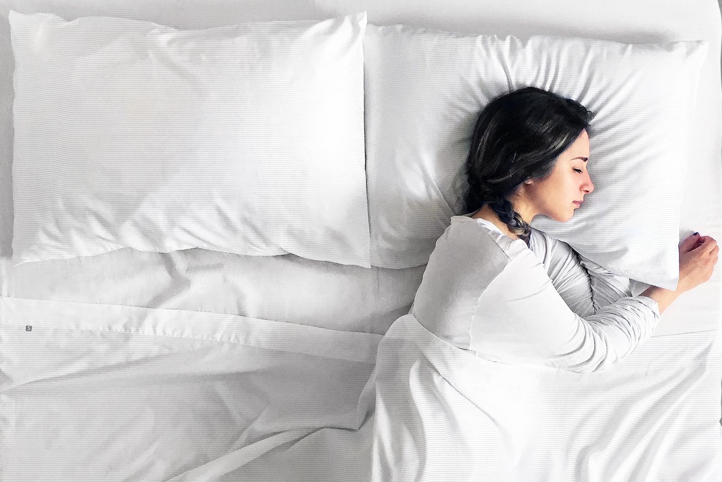 woman sleeping peacefully in white bed sheets