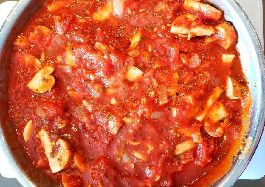 Bowl of tomato sauce with onion and mushrooms
