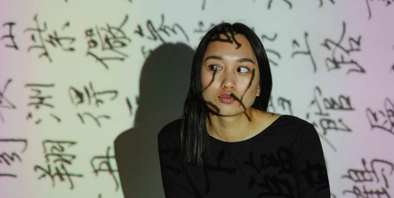 an asian girl with her gaze averted with text projected onto her